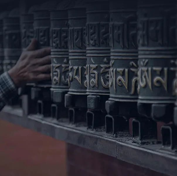 A hand is touching Tibetian prayer wheels.