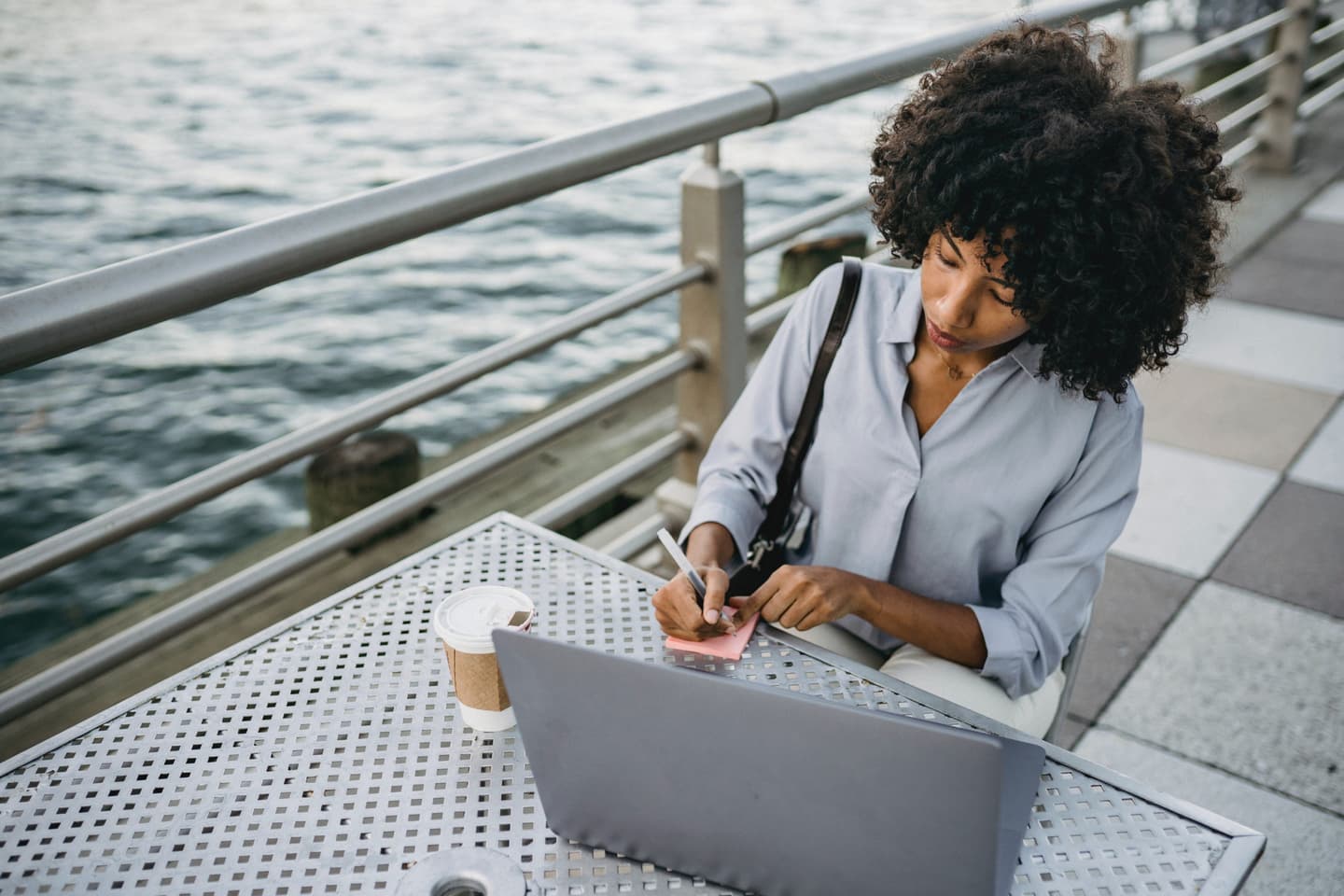 Image of woman in front of her laptop writing down notes