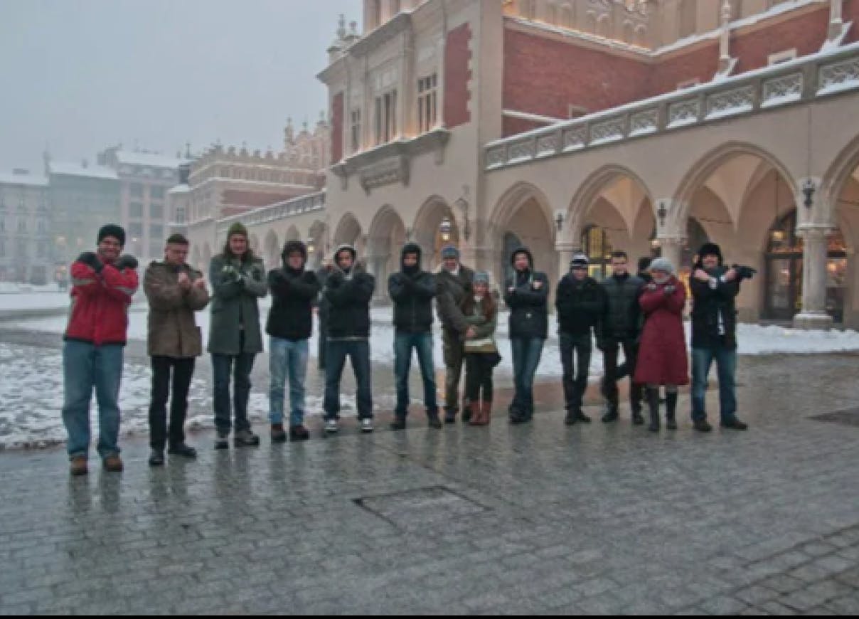 Members of the Xfive Team at the Krakow Market Square posing with hands crossed, presenting the letter "X"