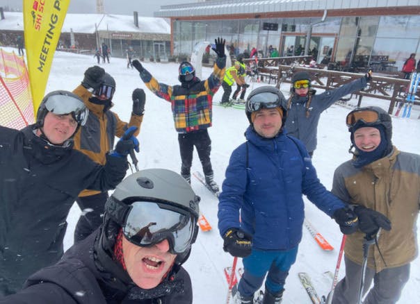 A group photo of the Xfive team on the ski slope in Slovakian Tatras. They are raising their hands in a gesture of joy.