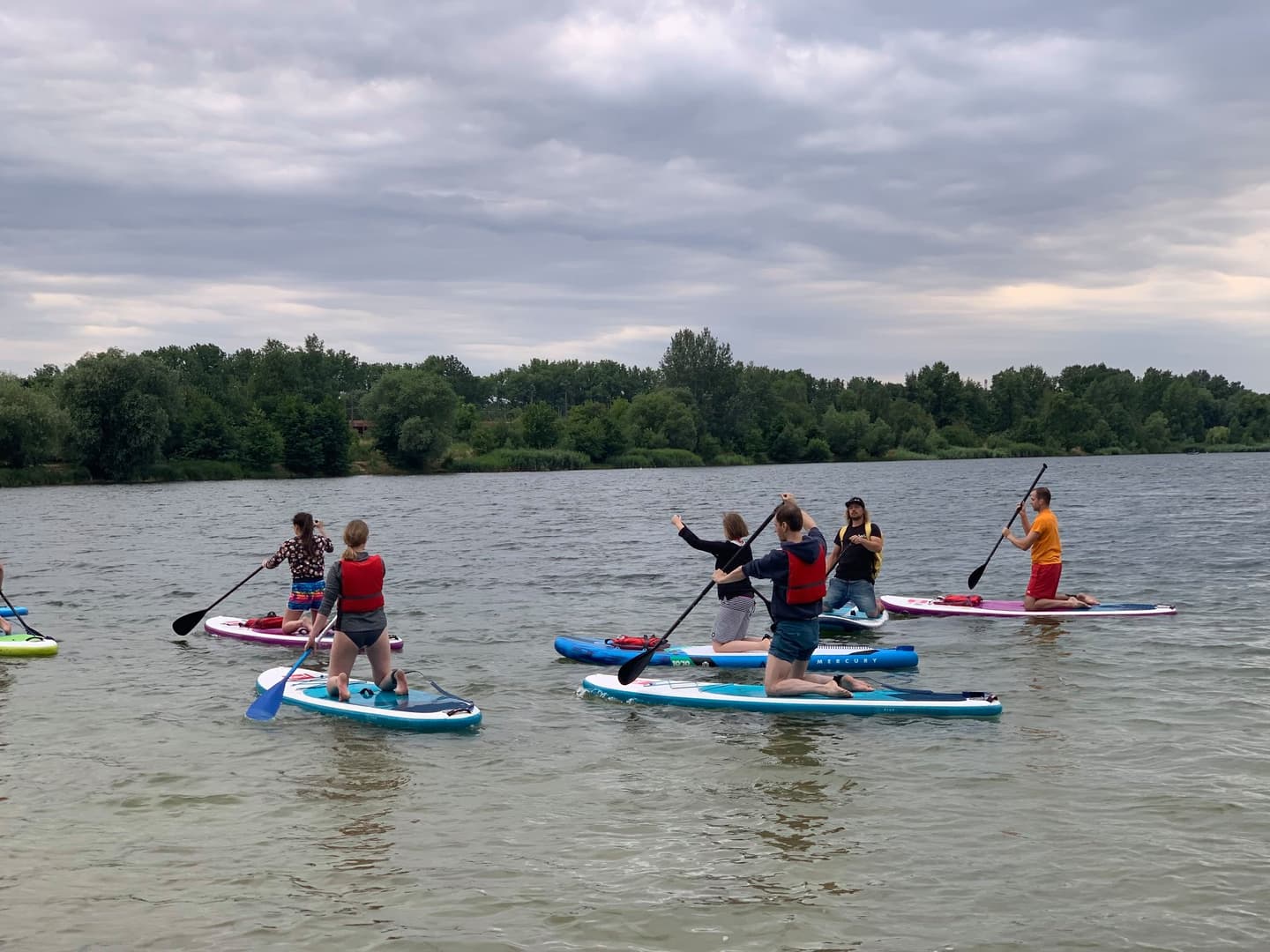 A group photo of the Xfive team sailing SUP boards on a lake.